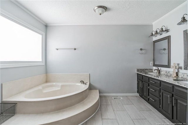 bathroom featuring double sink vanity, ornamental molding, a tub to relax in, a textured ceiling, and tile patterned flooring