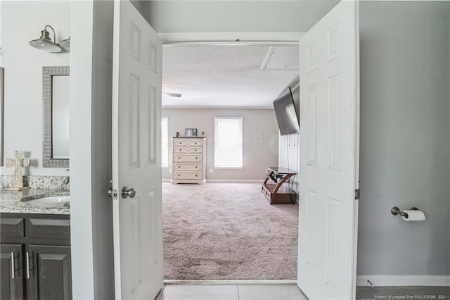 hallway with sink, a textured ceiling, and light carpet