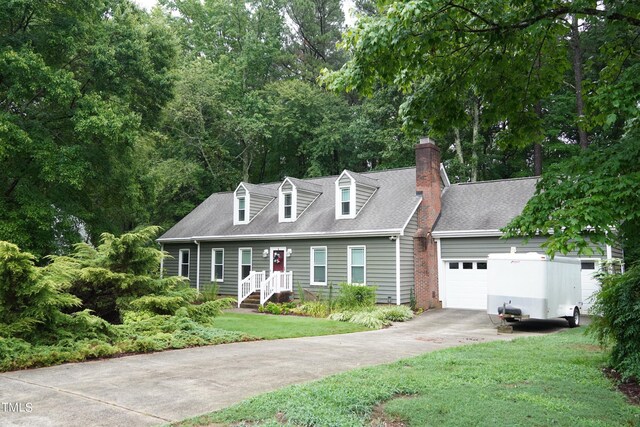 cape cod home with a front yard and a garage