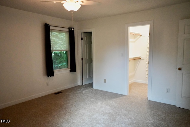 unfurnished bedroom with a spacious closet, ceiling fan, carpet floors, and a closet