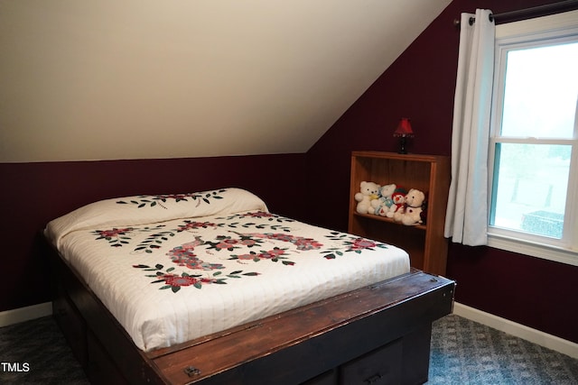 bedroom with dark colored carpet, multiple windows, and vaulted ceiling