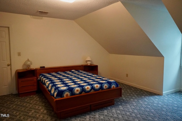 bedroom featuring dark carpet, vaulted ceiling, and a textured ceiling