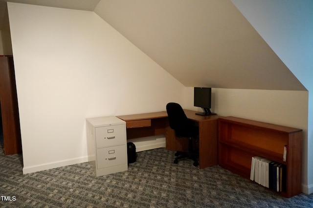 unfurnished office featuring dark carpet, lofted ceiling, and built in desk