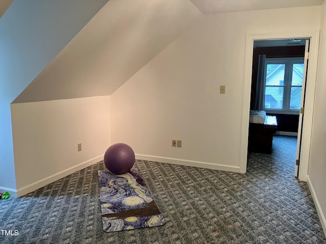 additional living space featuring lofted ceiling and dark colored carpet