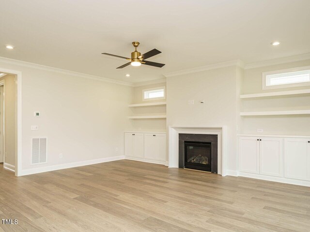205 Wash Hollow Dr, Wendell, NC 27591 - unfurnished living room featuring ceiling fan, a wealth of natural light, ornamental molding, light hardwood / wood-style floors, and built in shelves