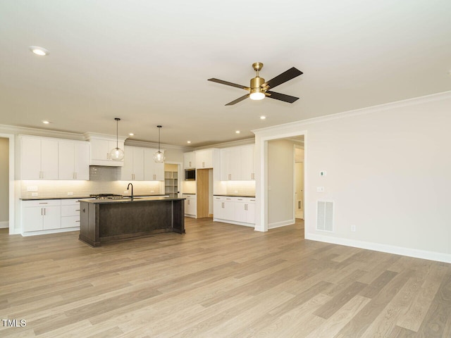 205 Wash Hollow Dr, Wendell, NC 27591 - kitchen with light hardwood / wood-style floors, a kitchen island with sink, decorative backsplash, and white cabinets