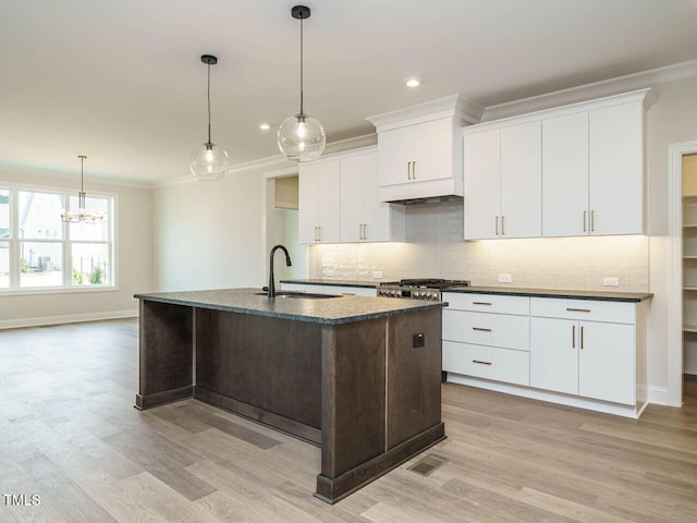 205 Wash Hollow Dr, Wendell, NC 27591 - kitchen featuring sink, crown molding, light hardwood / wood-style flooring, an island with sink, and decorative backsplash