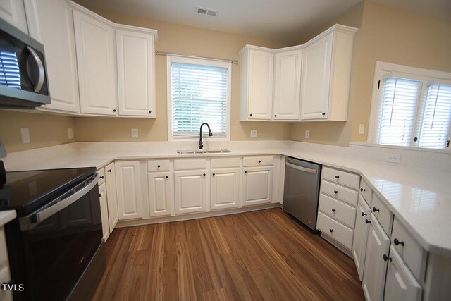 kitchen featuring appliances with stainless steel finishes, dark wood-type flooring, sink, and white cabinets