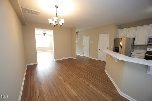 kitchen with hardwood / wood-style floors, a notable chandelier, hanging light fixtures, white cabinets, and appliances with stainless steel finishes