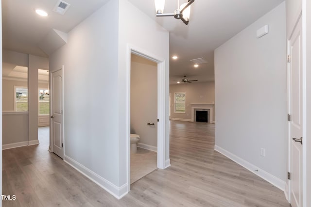 hallway with an inviting chandelier and light hardwood / wood-style flooring