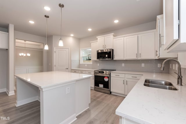 kitchen with white cabinetry, sink, a center island, a chandelier, and appliances with stainless steel finishes