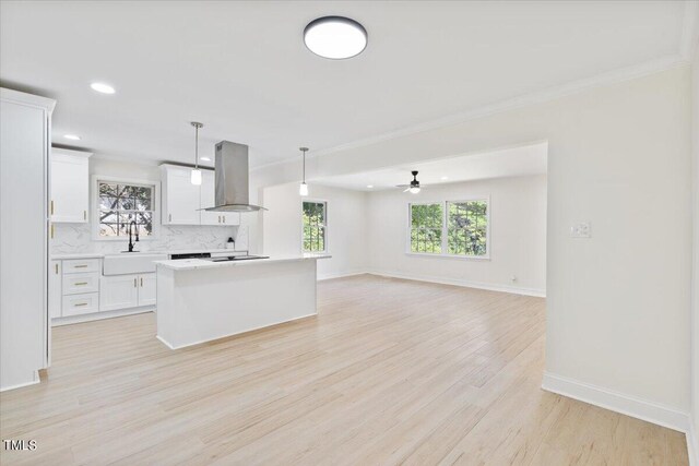 kitchen featuring white cabinets, exhaust hood, decorative light fixtures, and light hardwood / wood-style flooring