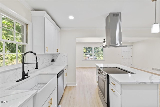 kitchen with appliances with stainless steel finishes, hanging light fixtures, backsplash, light hardwood / wood-style floors, and island exhaust hood