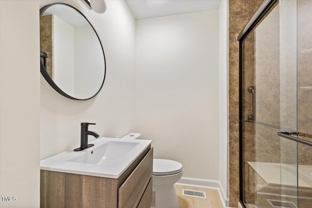 bathroom with vanity, walk in shower, hardwood / wood-style flooring, and toilet