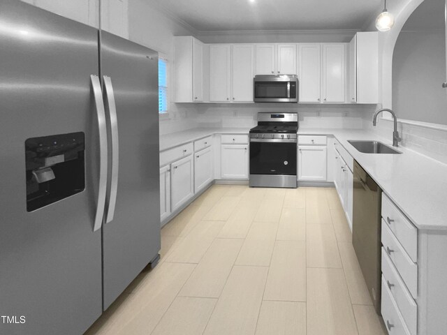 kitchen with crown molding, appliances with stainless steel finishes, sink, white cabinets, and decorative backsplash