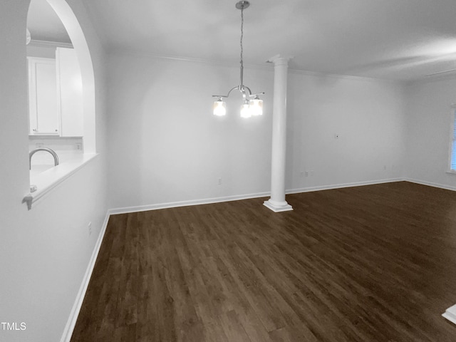 unfurnished dining area featuring ornamental molding, an inviting chandelier, ornate columns, and dark hardwood / wood-style flooring