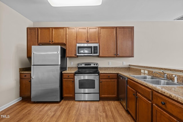 kitchen featuring appliances with stainless steel finishes, light hardwood / wood-style flooring, and sink