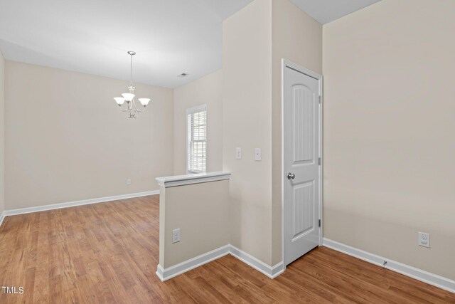 corridor with a chandelier and light wood-type flooring