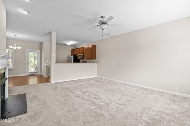 unfurnished living room featuring ceiling fan with notable chandelier and hardwood / wood-style floors