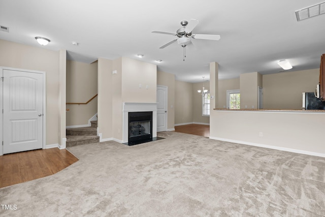 unfurnished living room featuring ceiling fan with notable chandelier and carpet floors