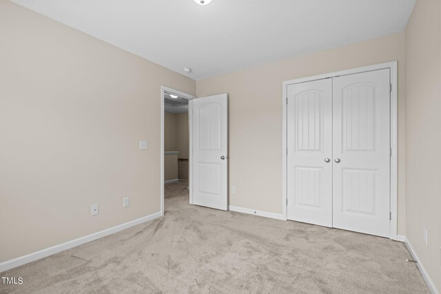 unfurnished bedroom featuring light carpet and a closet