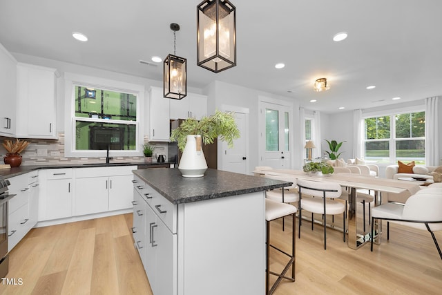 kitchen with a center island, light hardwood / wood-style floors, hanging light fixtures, and white cabinets