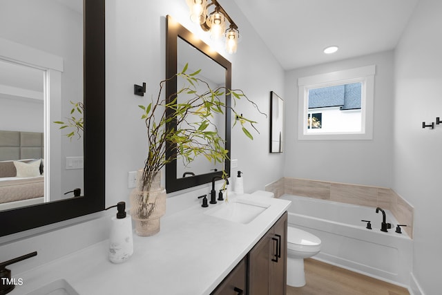 bathroom featuring vanity, hardwood / wood-style floors, a tub, and toilet