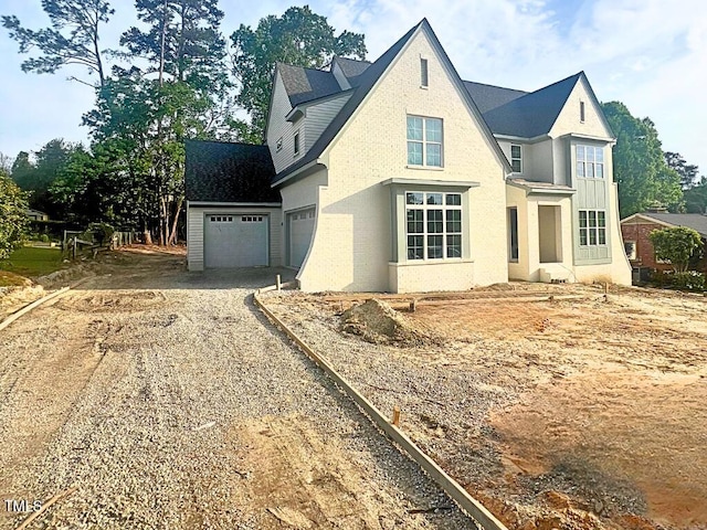 traditional-style house featuring a garage, brick siding, and dirt driveway
