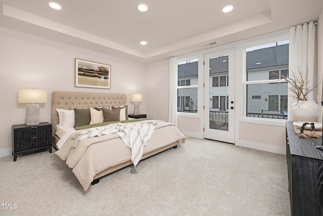 bedroom with carpet floors, access to exterior, and a raised ceiling