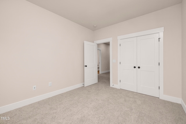 unfurnished bedroom with light colored carpet and a closet