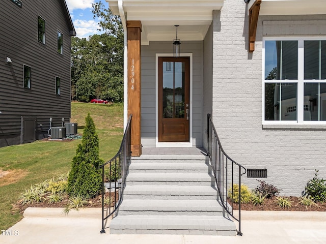 doorway to property with central AC and a lawn