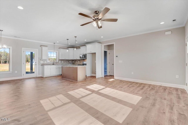 unfurnished living room with crown molding, light wood-style flooring, baseboards, and ceiling fan with notable chandelier