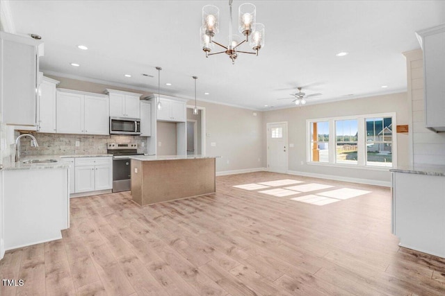 kitchen featuring light wood finished floors, tasteful backsplash, appliances with stainless steel finishes, open floor plan, and a sink