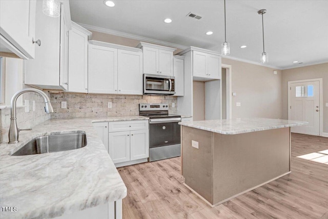 kitchen featuring visible vents, light wood-style flooring, appliances with stainless steel finishes, ornamental molding, and a sink