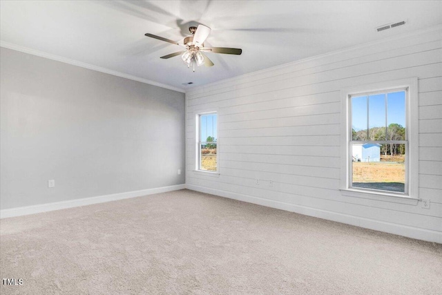 unfurnished room with ornamental molding, a wealth of natural light, visible vents, and carpet flooring