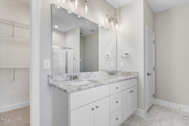 bathroom with double vanity, a stall shower, a sink, and baseboards