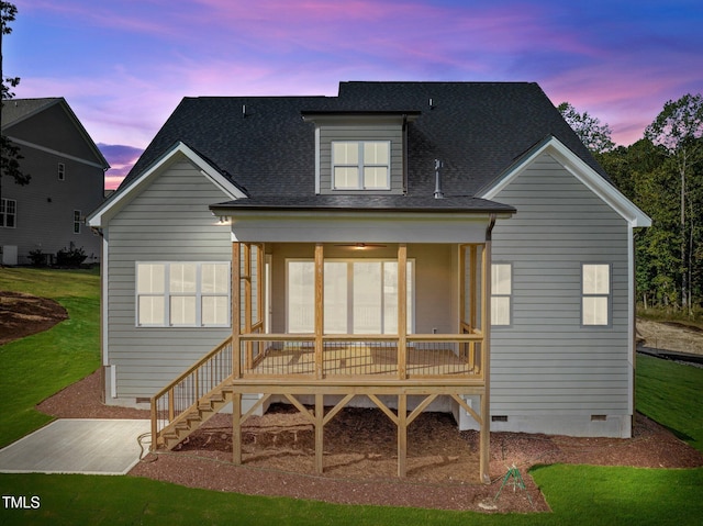 back house at dusk featuring a yard and a sunroom