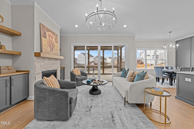 living room featuring ornamental molding, a stone fireplace, light wood-type flooring, and a chandelier