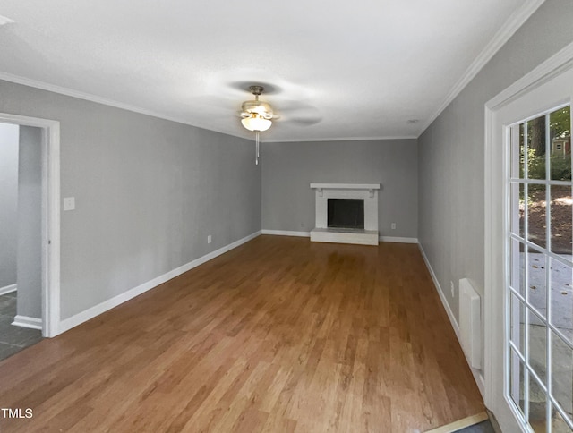 unfurnished living room with a fireplace, wood-type flooring, ceiling fan, and crown molding