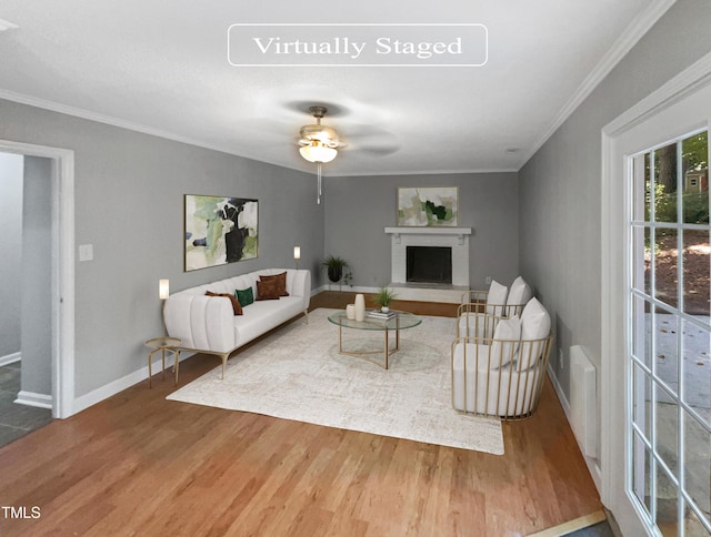 living room with a fireplace, ceiling fan, wood-type flooring, and ornamental molding