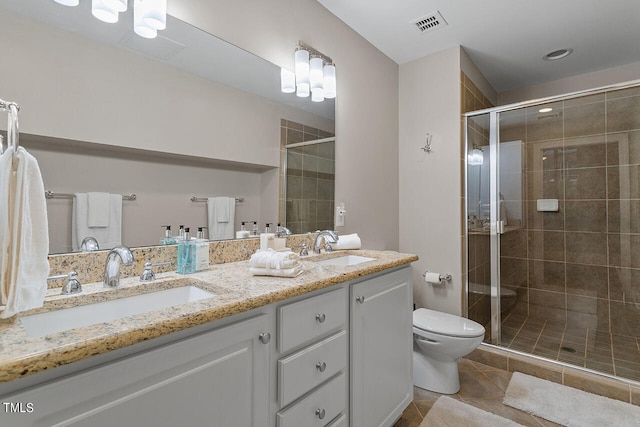 bathroom featuring tile patterned floors, toilet, a shower with door, and double vanity