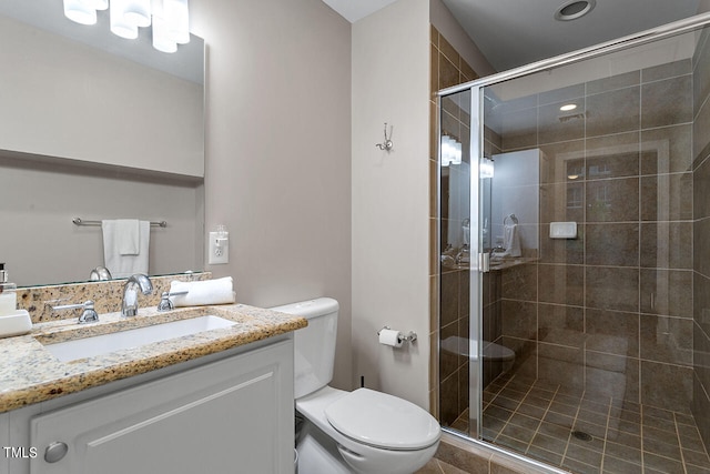 bathroom with a shower with shower door, toilet, and vanity