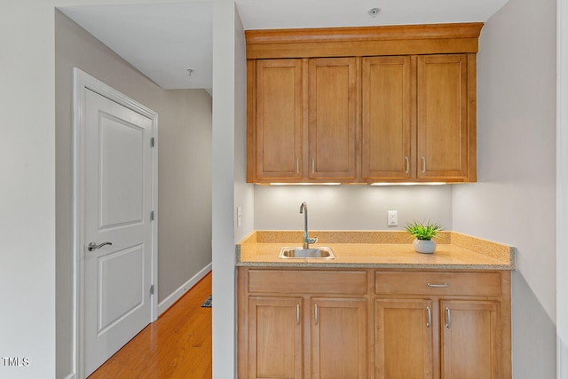 kitchen featuring sink, light wood-type flooring, and light stone countertops