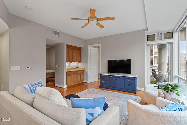 living room with light wood-type flooring and ceiling fan