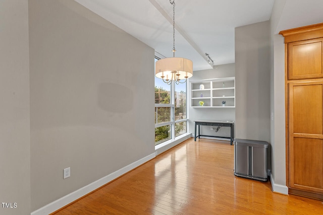 unfurnished dining area with a notable chandelier and light hardwood / wood-style floors