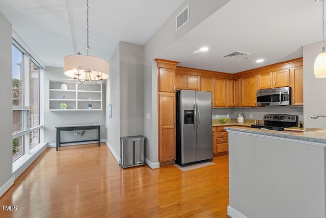 kitchen featuring decorative light fixtures, plenty of natural light, light wood-type flooring, and stainless steel appliances