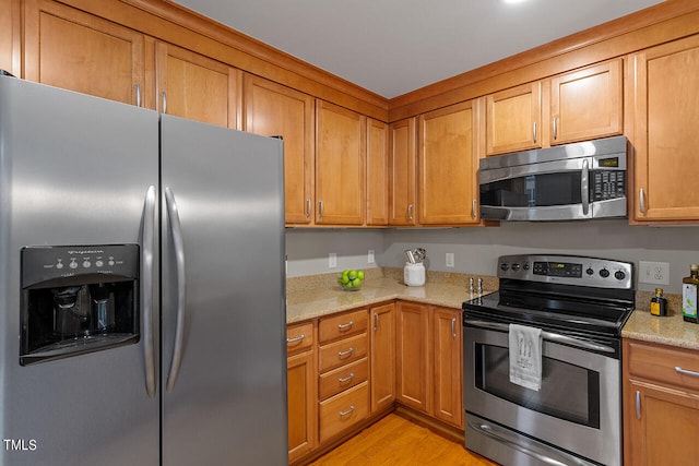 kitchen featuring light stone counters, light wood-type flooring, and stainless steel appliances