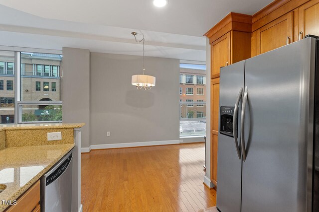 kitchen featuring appliances with stainless steel finishes, light wood-type flooring, a healthy amount of sunlight, and decorative light fixtures