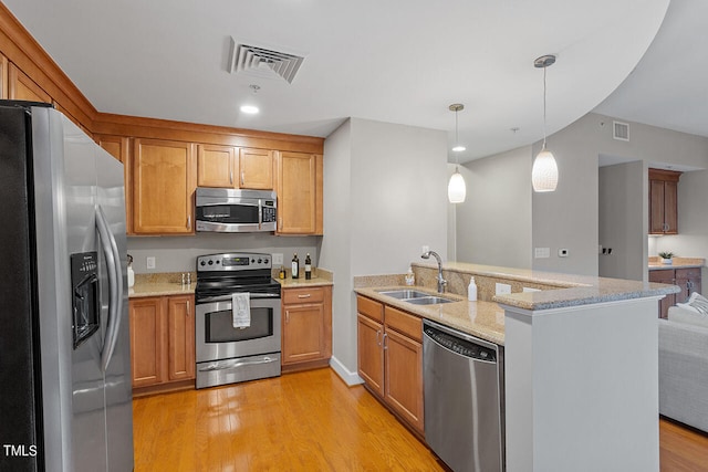 kitchen featuring appliances with stainless steel finishes, light hardwood / wood-style flooring, decorative light fixtures, and sink