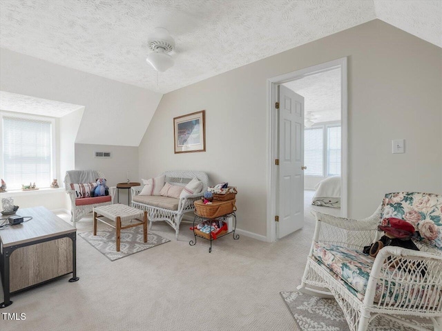 carpeted living room featuring vaulted ceiling, ceiling fan, and a textured ceiling